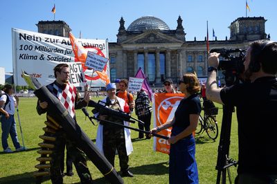 Ein Kamerateam interviewt den Lehrer im Camouflage, im Hintergrund ist das Aktionsbild und der Reichstag zu sehen.