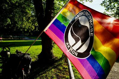 Eine Regenbogenfahne mit einem Antifa-Logo und dem umrundenden Text "Antihomophobe Aktion" hängt im Camp