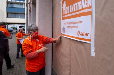 An der mit Packpapier überklebten Fensterscheibe hängt ein Schild im Stil eines Wohnungsverkaufsschildes mit der Aufschrift "Zu Enteignen"