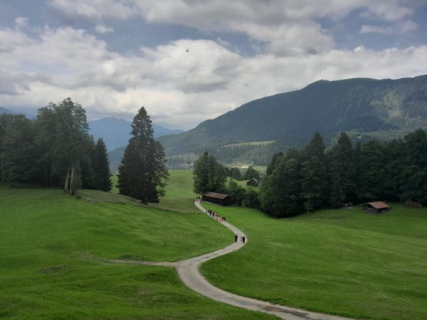 Blick über einen Weg, der sich durch die Alpen ins Tal herunterschlänget
