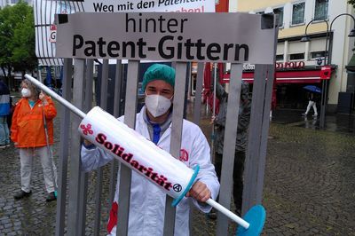 Arzt mit Solidaritätsspritze ist in einem Käfig eingesperrt mit der Überschrift "hinter Patent-Gittern"