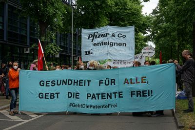 Das Fronttransparent der Demo mit dem Titel "Gesundheit für alle, gebt die Patente Frei!", dahinter ist ein Transparent mit dem Slogan "Pfizer & Co. enteignen" zu sehen