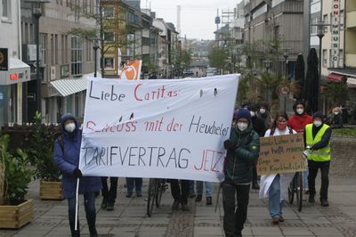 Fronttransparent eines Demozuges mit dem Slogan "Liebe Caritas, Schluss mit der Heuchelei: Tarifvertrag jetzt"