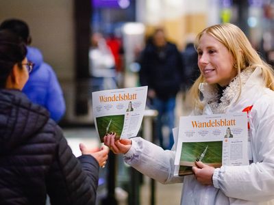 Eine Attac-Aktivistin verteilt die gefakete Zeitung "Wandelsblatt"