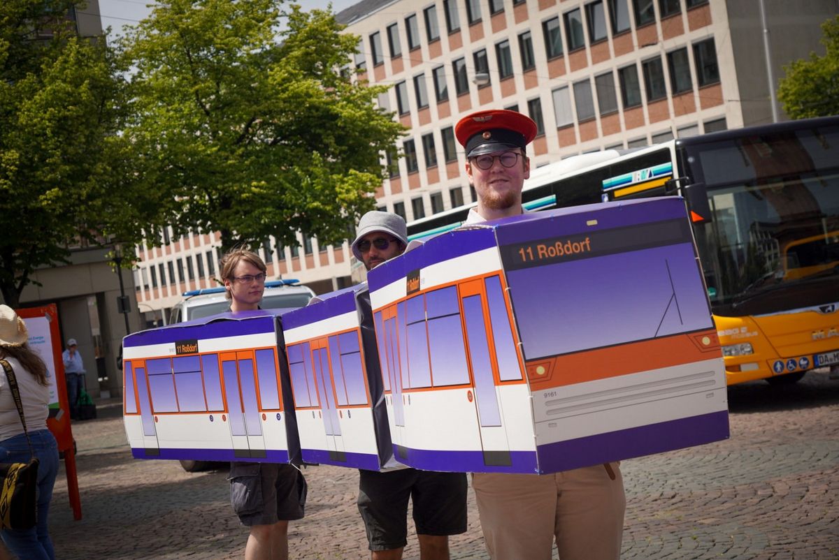 Drei Menschen stehen in einer tragbaren Darmstädter Straßenbahn.