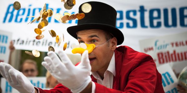 Ein Mensch im Dagobert-Duck-Kostüm wirft Goldmünzen in die Höhe