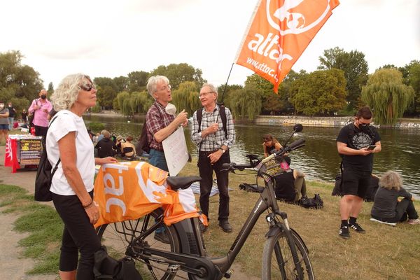 Mehrere Attacies stehen mit Fahnen gut gelaunt bei der Kundgebung in Berlin, im Hintergrund der Landwehrkanal
