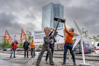 Ein Aktivist in Attac-Jacke versucht Lagarde und Nagel daran zu hindern mit dem Hammer auf das Windrad einzuschlagen.