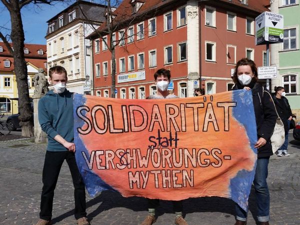 Junge Attacis halten ein Banner mit der Aufschrift "Solidarität statt Verschwörungsmythen"