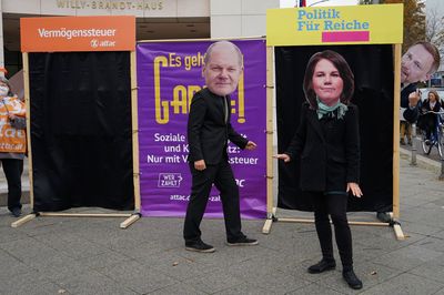 Vor dem Willy-Brandt-Haus stehen Menschen, die als Annalena Baerbock und Olaf Scholz verkleidet sind unschlüssig vor zwei Türen die mit "Vermögenssteuer" und "Politik für Reiche" überschrieben sind. Christian Lindner versucht sie zur Politik-für-Reiche-Tür zu locken