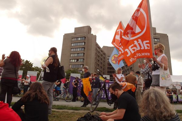 Im Vorderrund die Demo mit Attac-Fahnen, im Hintergrund ist das Urban-Krankenhaus zu sehen
