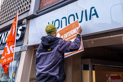 Attac Aktivist bringt ein "Zu Enteignen"-Schild über das Vonovia-Schild an