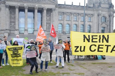 Vor dem Reichstag steht eine kleine Demogruppe und hält ein großes Transparent mit der Aufschrift "Nein zu CETA"