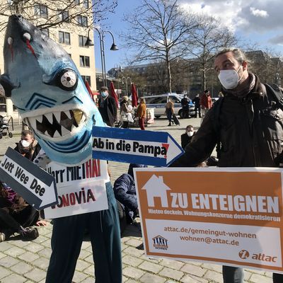 links steht ein Mensch im Miethaikostüm, daneben ein Attacke mit einem Schild auf dem "Zu Enteignen" steht