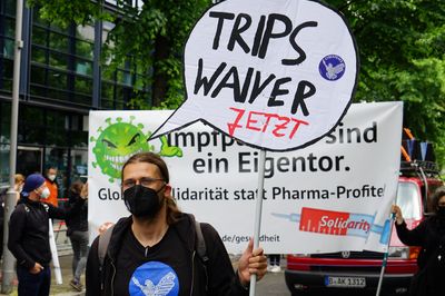 Ein Mensch hält ein Schild in Form einer Sprechblase mit der Aufschrift "TRIPS-Waiver jetzt" hoch