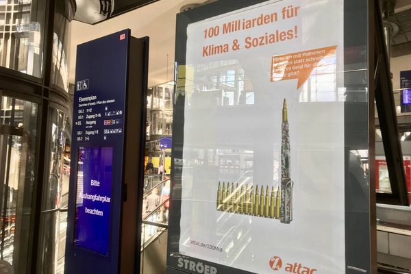 Im Berliner Hauptbahnhof hängt ein geadbustetes Werbeplakat auf dem ein Füller mit einem Patronengurt ist mit einer Sprechblase auf der "Muss ich erst schießen, damit es Geld für Bildung gibt?" steht. Als Überschrift steht "100 Milliarden für Klima und Soziales!" auf dem Plakat