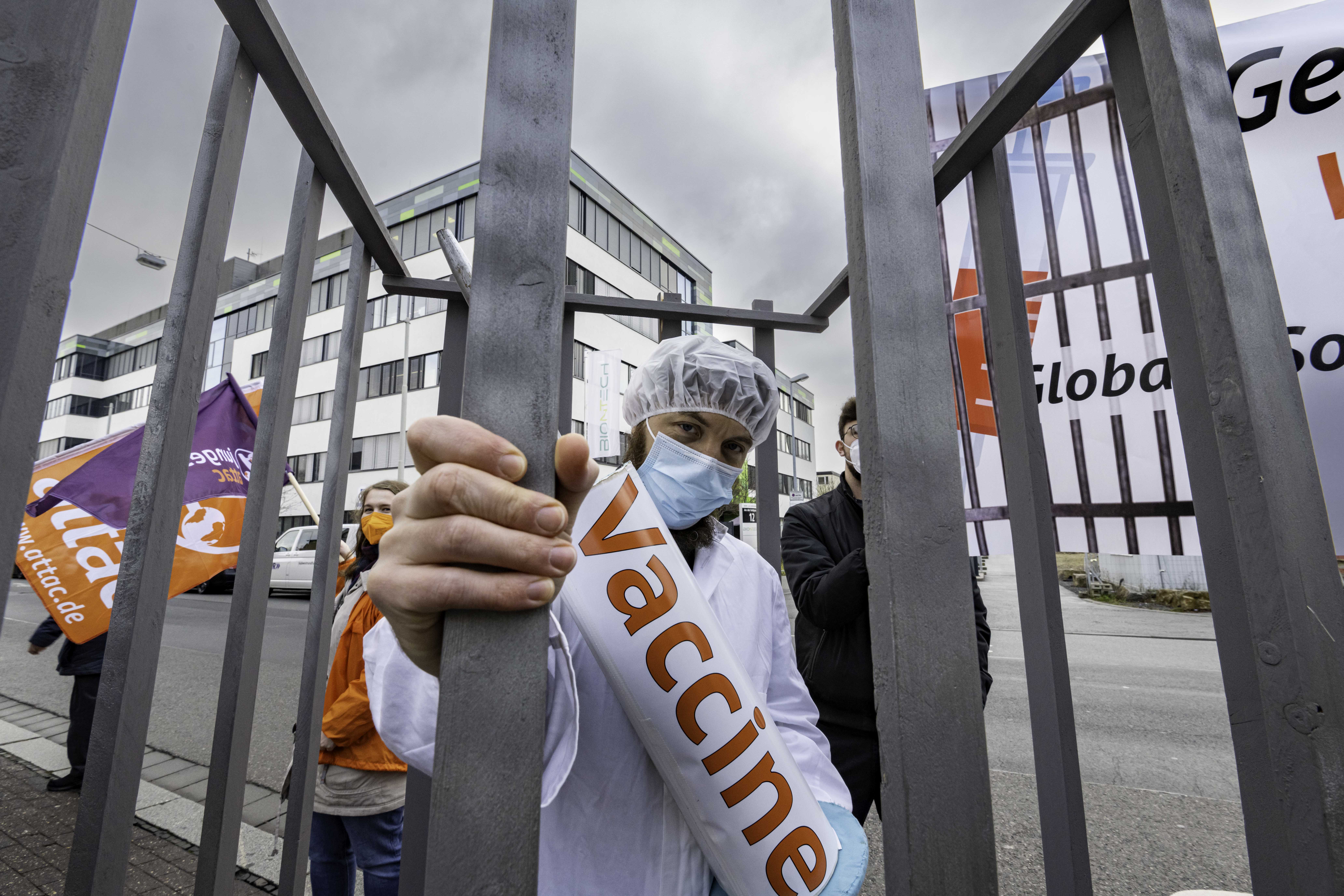 Ein als Arzt verkleideter Aktivist mit einer Übergroßen Impfspritze ist hinter Gittern gefangen.