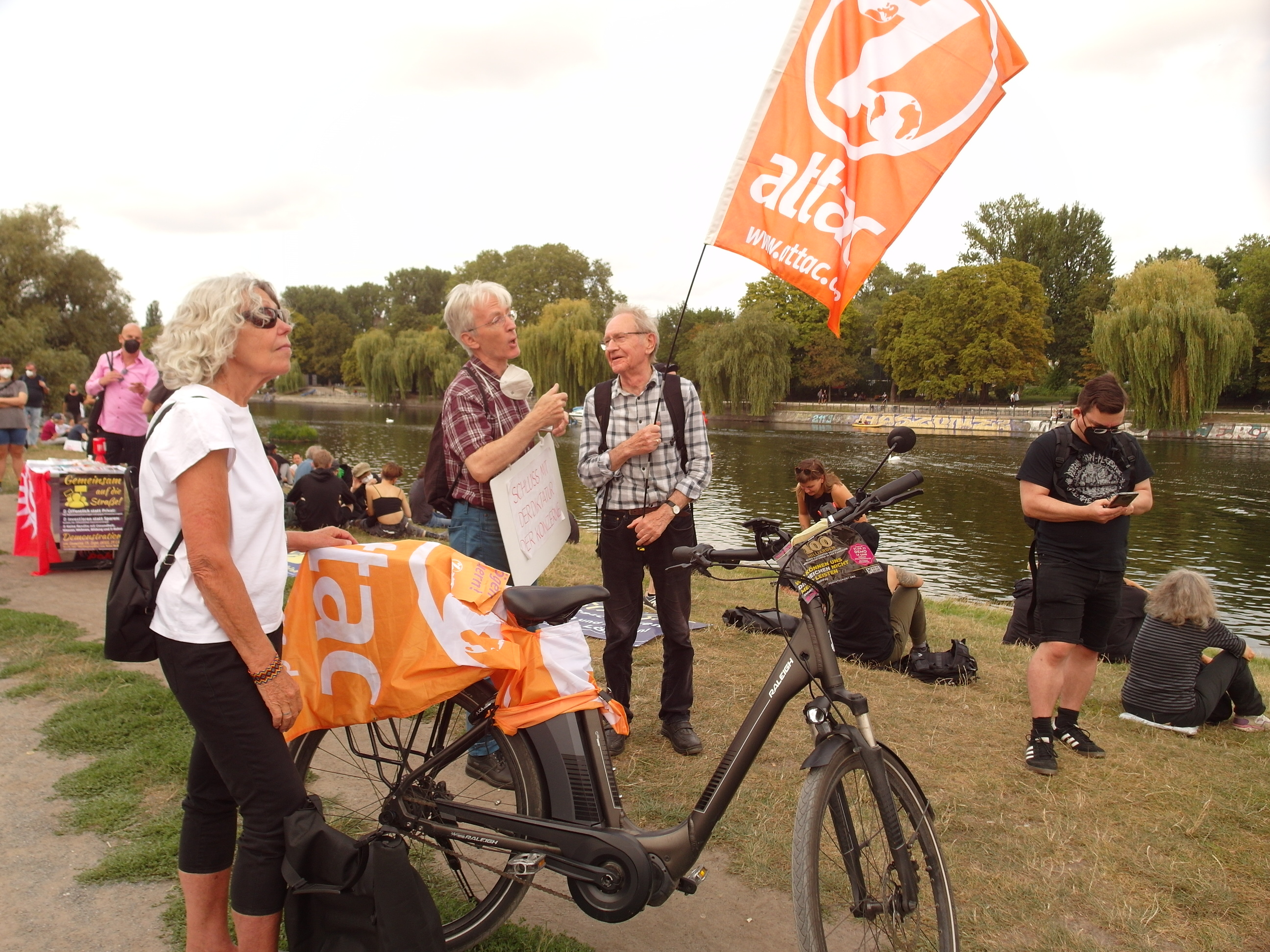 Mehrere Attacies stehen mit Fahnen gut gelaunt bei der Kundgebung in Berlin, im Hintergrund der Landwehrkanal