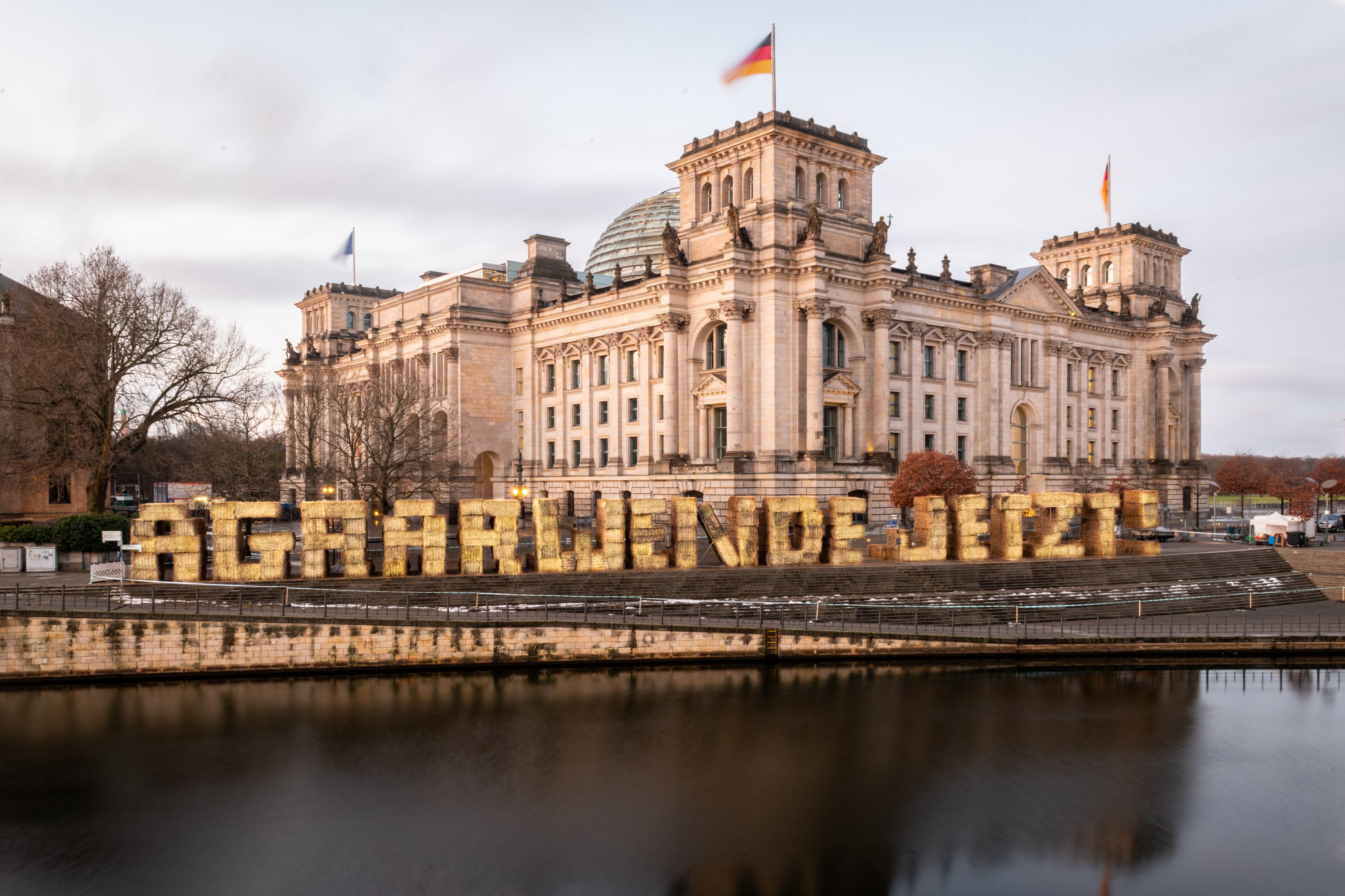 vor dem Reichstag aus Strohballen geformt stehen die Buchstaben "AGRARWENDE JETZT"